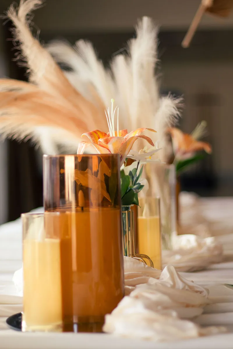 Amber glassware, lilies and pampas along a white linen runner