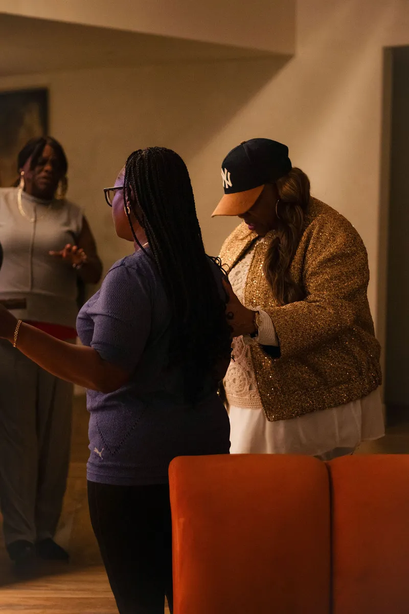 One woman praying over another with a hand on her arm in warm lamplight