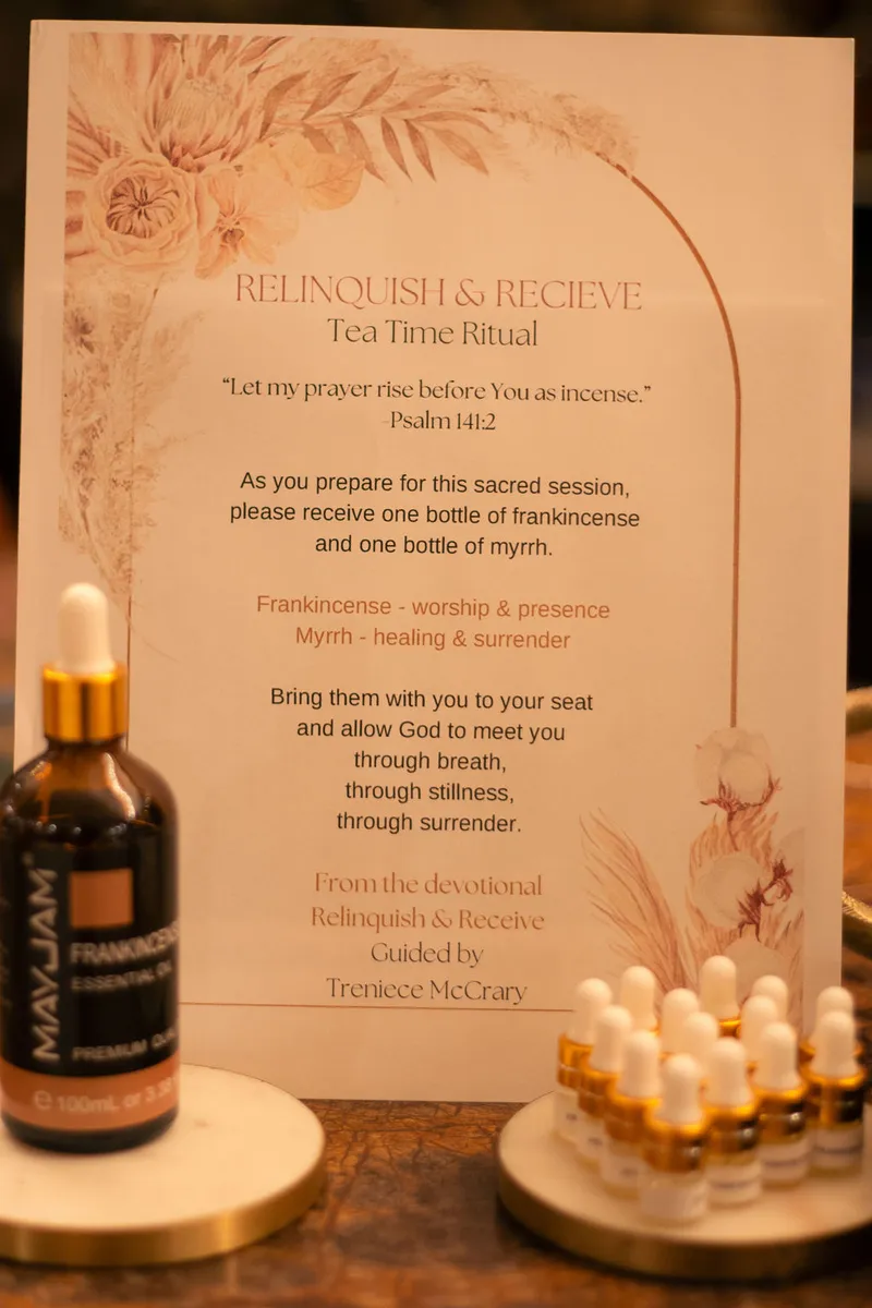 A Relinquish and Receive tea time ritual card beside bottles of frankincense and myrrh
